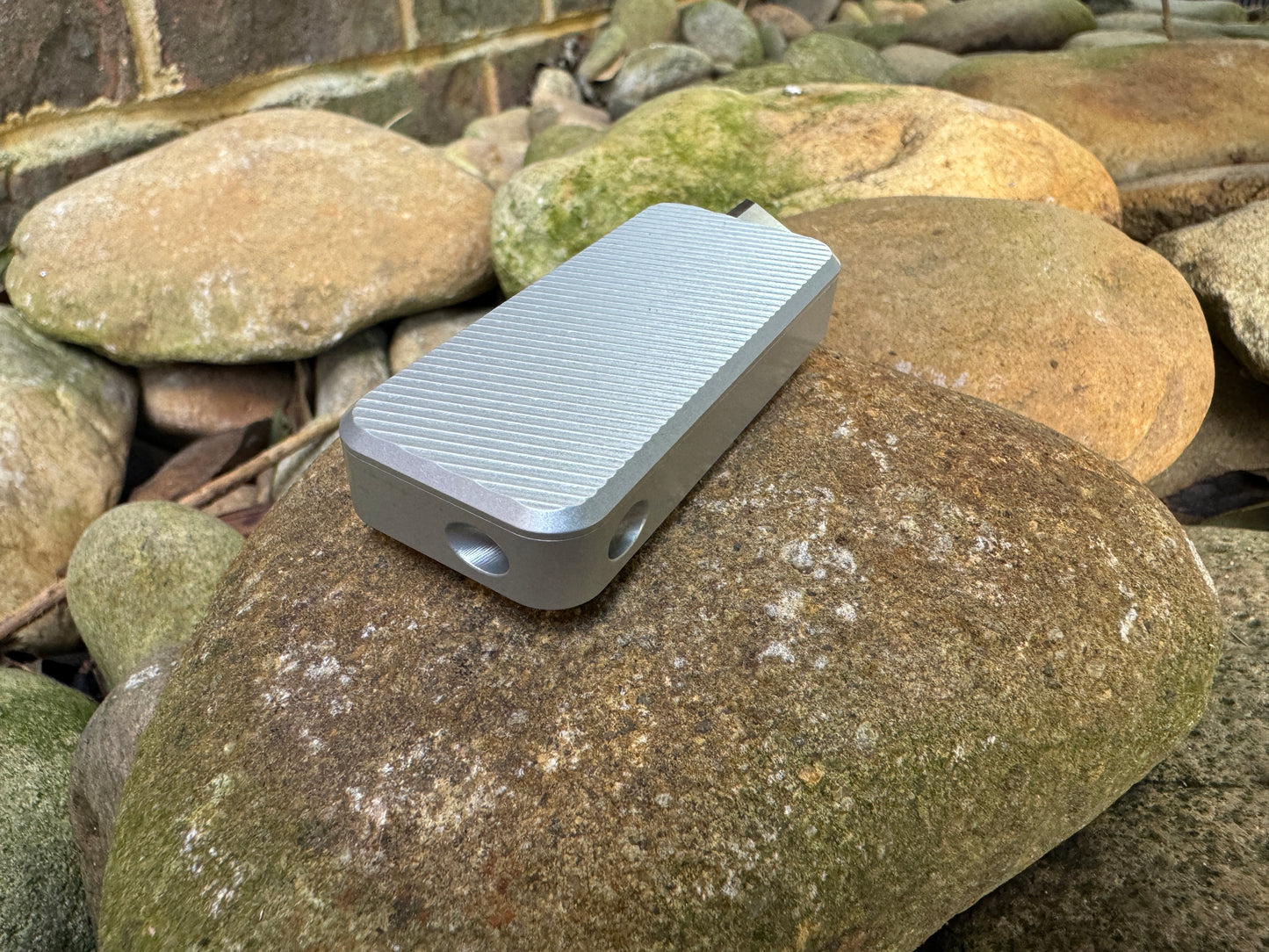 Gray RiveryMFG Zero custom combination utility knife with file pattern and extended blade on stones.