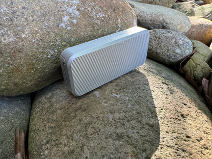 Gray RiveryMFG Zero-6061 Aluminum with lanyard hole utility knife with file pattern side view on stones 