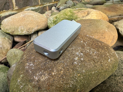 Gray RiveryMFG Zero custom combination utility knife with file pattern and extended blade on stones.