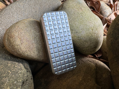 RiveryMFG Gray Zero utility knife with grenade pattern handle on stones.