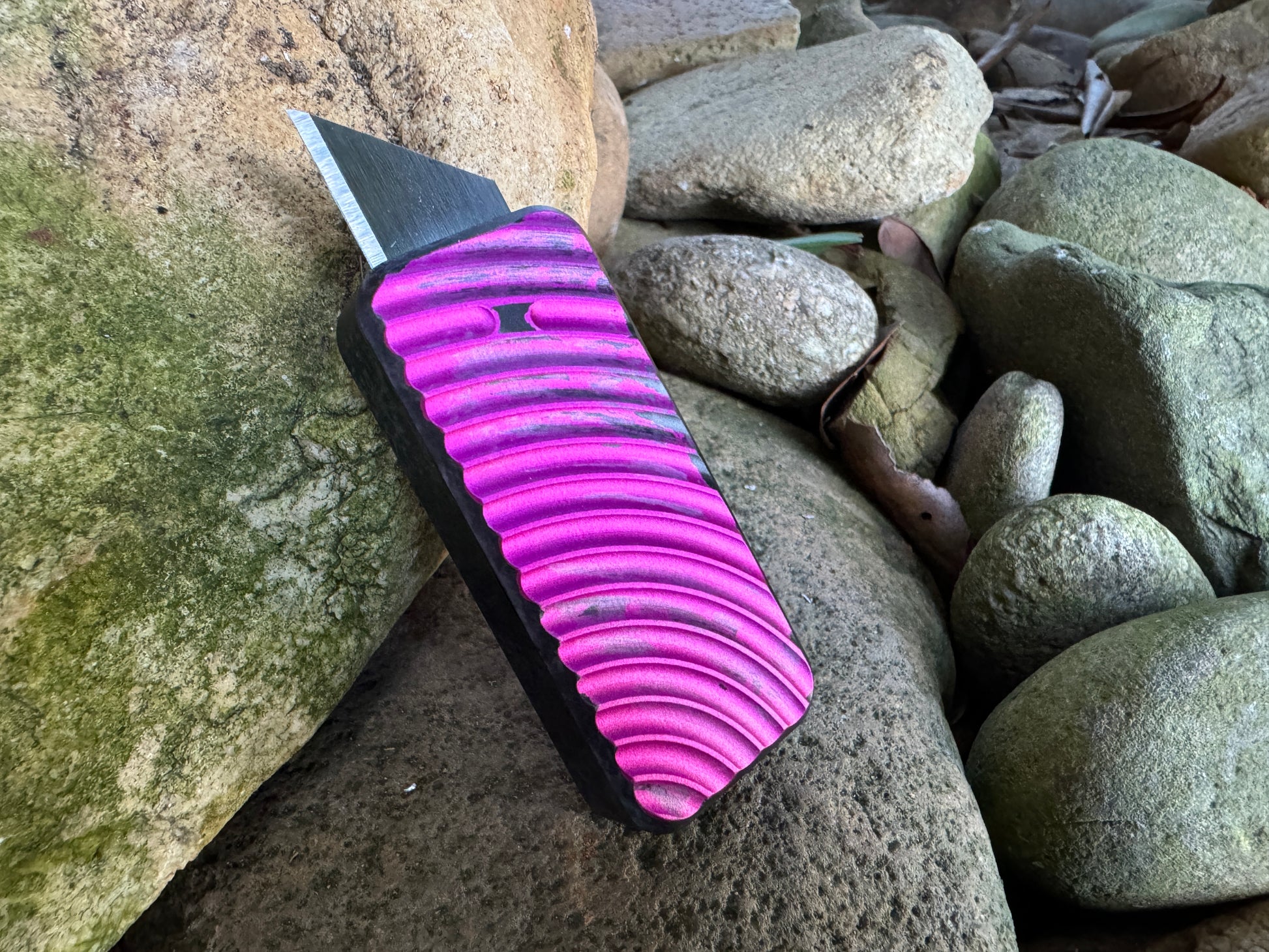 Pink and charcoal anodized RiveryMFG Zero retractable utility knife.